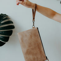 Convertible crossbody grey leather handbag, worn as a clutch