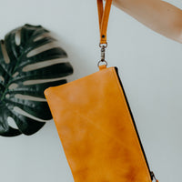 Tanned leather convertible crossbody handbag worn as a clutch